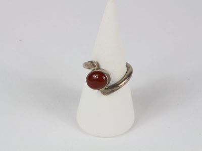 silver ring with a red stone on it on a white cone