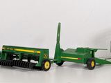 a green toy tractor and a green trailer with a hay bale on it