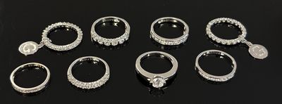 several different types of silver rings on a black surface