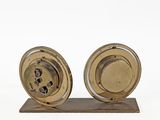 two clocks on a wooden stand on a white surface