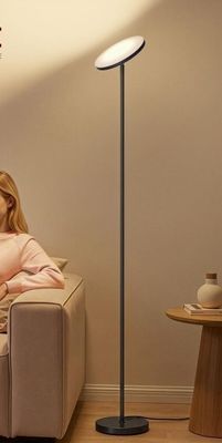 une femme assise sur un canapé dans un salon, à côté d'une lampe