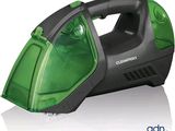 aspirateur à main vert et noir posé sur une surface blanche