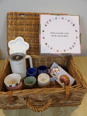un panier en osier rempli de tasses à café et d'un petit mot