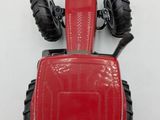 a red toy tractor that is on a white surface