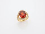 a red stone and diamond ring on a white surface