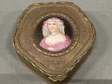 a gold box with a picture of a woman in a pink dress