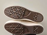 the bottom view of a pair of white sneakers on a black box