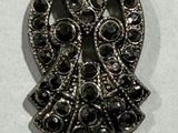 a silver owl brooch with black stones on it
