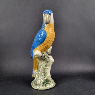 a figurine of a blue and yellow parrot on a branch
