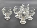 six clear glass goblets sitting on top of a black table