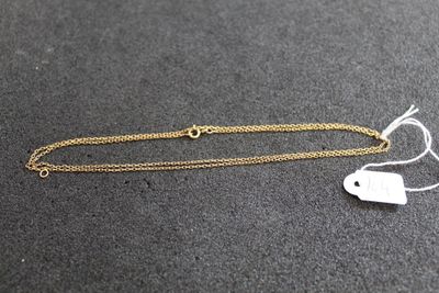 une petite étiquette blanche suspendue à une chaîne dorée, à côté d'une autre petite étiquette blanche posée sur une surface noire