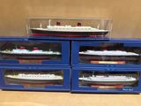 trois boîtes bleues contenant chacune une maquette de paquebot de croisière