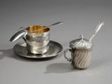 une tasse et une soucoupe en argent, avec une cuillère posée sur la soucoupe