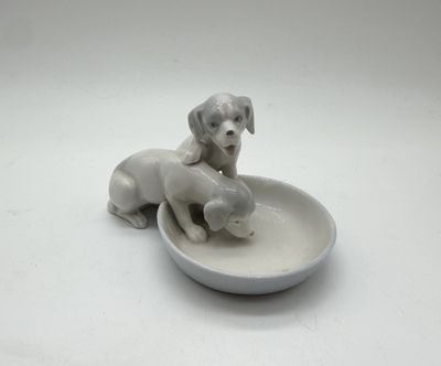 porcelain figurine of two dogs in a bowl on a white surface