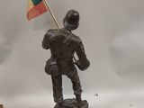 figurine of a man holding a flag on a wooden base
