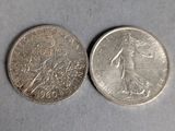 two silver coins sitting side by side on a white surface