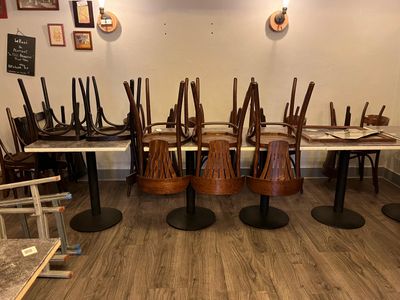 de nombreuses chaises et tables dans une pièce où est accrochée une horloge au mur
