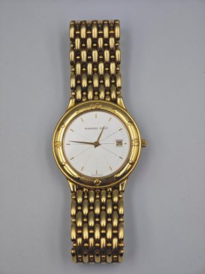 gros plan d'une montre-bracelet en or sur une surface blanche