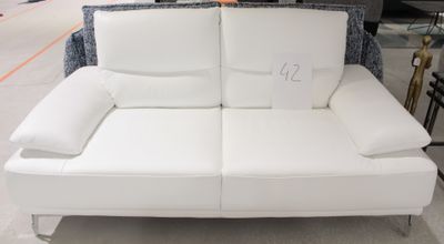 un canapé en cuir blanc avec des coussins, dans un magasin