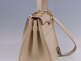 the small beige bag is sitting on a white surface