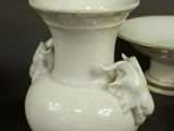 a white vase and a bowl sitting next to each other