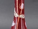 a red vase with a flower on it on a table