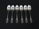 six spoons are lined up in a row on a black surface