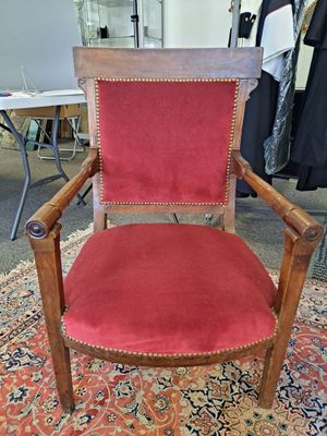 une vieille chaise en bois recouverte de velours rouge, posée sur un tapis