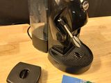 une cafetière noire posée sur une table à côté d'une télécommande