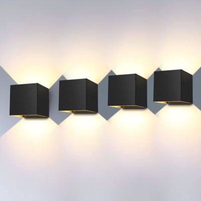 trois lampes cubiques noires fixées au mur, à côté d'un mur blanc