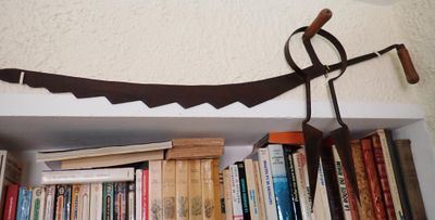 une étagère sur laquelle sont posés des livres et une faux en métal