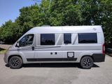 a silver van parked in a parking lot with trees in the background