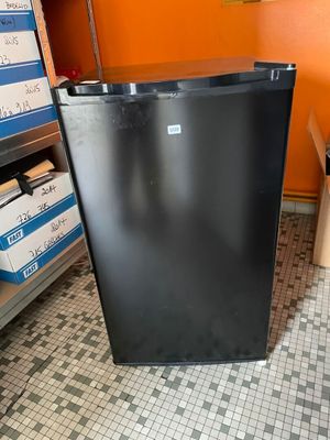 un petit réfrigérateur noir dans une pièce aux murs orange