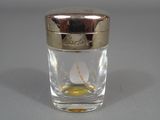 a small glass with a gold lid and a flower in it