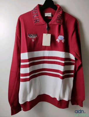 a red and white sweater hanging on a hanger on a wall