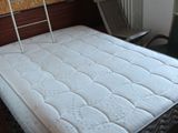 un matelas posé à même le sol dans une pièce où se trouve une échelle