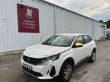 une voiture blanche garée devant un immeuble sur lequel est accrochée une pancarte