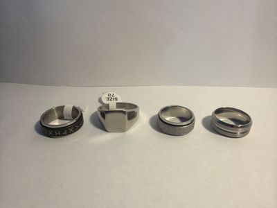four different rings are sitting on a table with a price tag