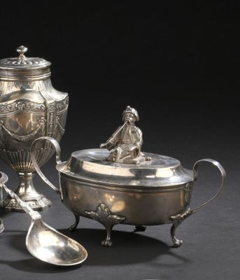 une théière en argent et une cuillère en argent posées sur une table