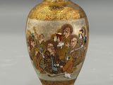 a gold vase with a painting on it sitting on a table