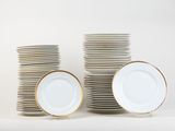 a stack of white plates with gold rims on a white surface