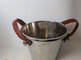 a metal bucket with a leather handle on a table