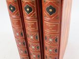 trois livres sont empilés sur une surface blanche
