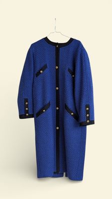 blue and black coat on a hanger against a white wall