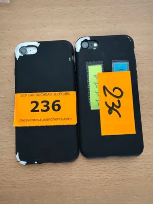 two black iphone cases with yellow stickers on them sitting on a table