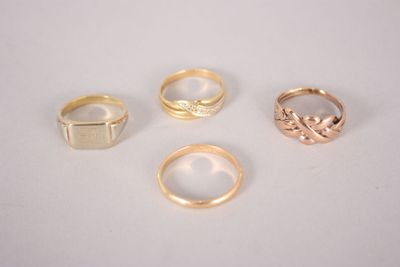 four gold rings on a white surface with a diamond in the middle