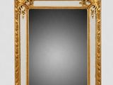 un miroir à cadre doré posé sur un mur blanc