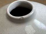 a white vase with a hole in it on a table