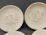 four white plates with drawings of a woman and a dove on them