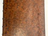 un vieux livre en cuir marron posé sur une table blanche